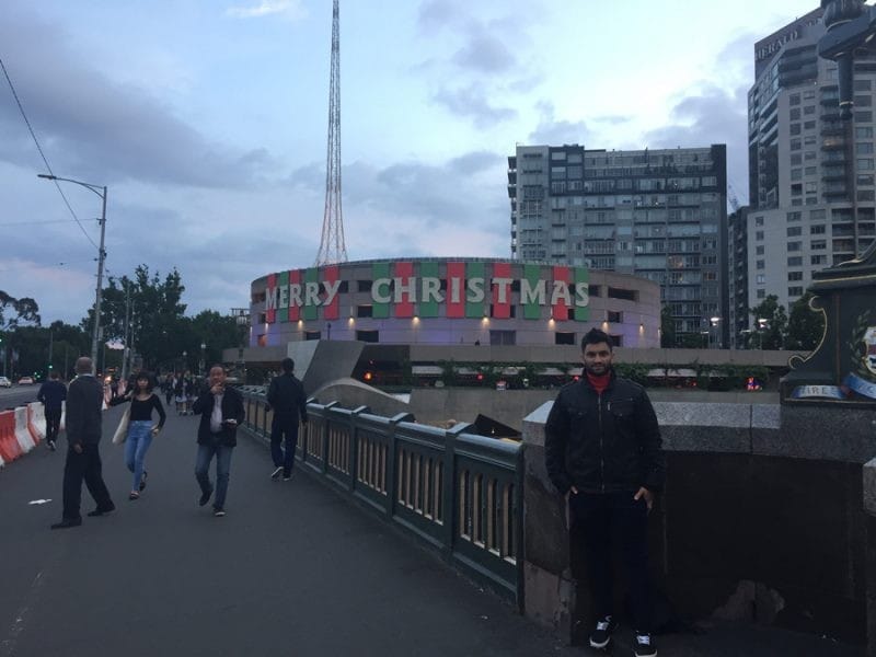 Dani en Melbourne estudiante chico posando delante de un monumento en Melbourne y de fondo el cielo nublado